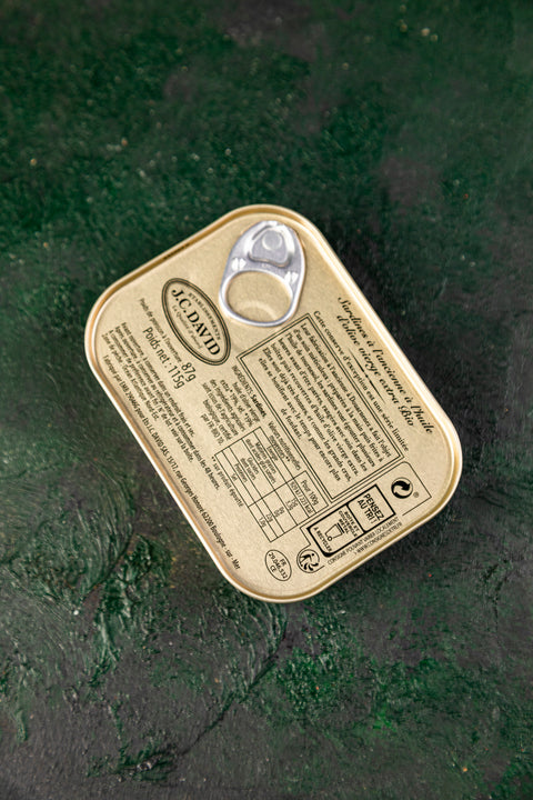 Cans of JC David organic aged sardines in olive oil, 115g, with open can showing sardines inside, branded as Śledzie z Bornholmu.